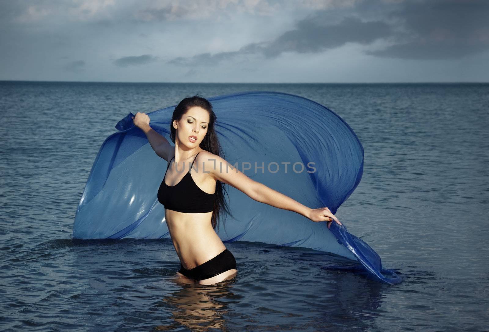 Lady with perfect body dancing in the sea with blue fabric