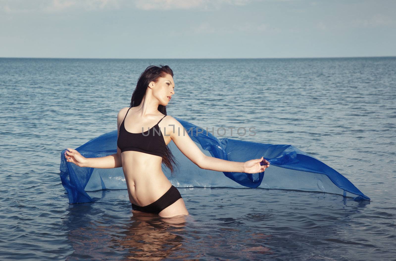 Woman with blue fiber dancing in the sea