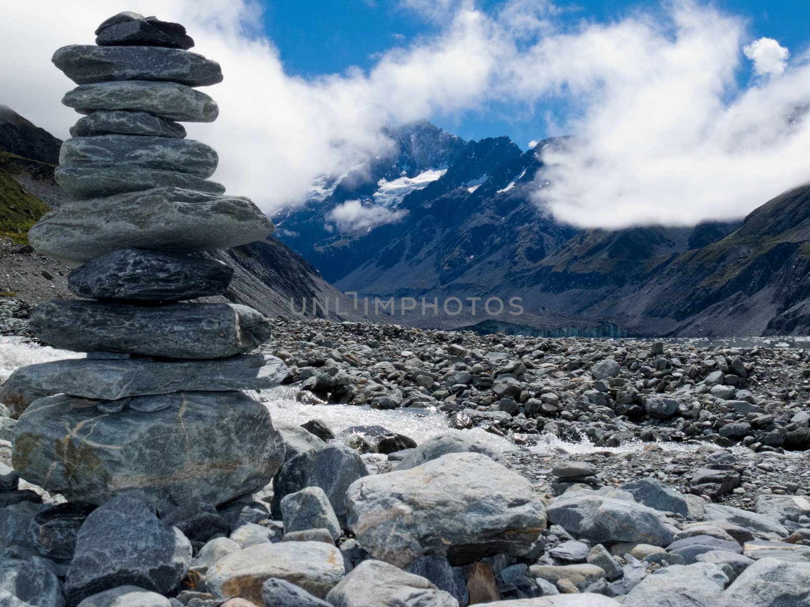 Rock cairn in Hooker Valley on a trail leading to Aoraki  Mount Cook  highest peak of Southern Alps  an icon of New Zealand partially covered in clouds