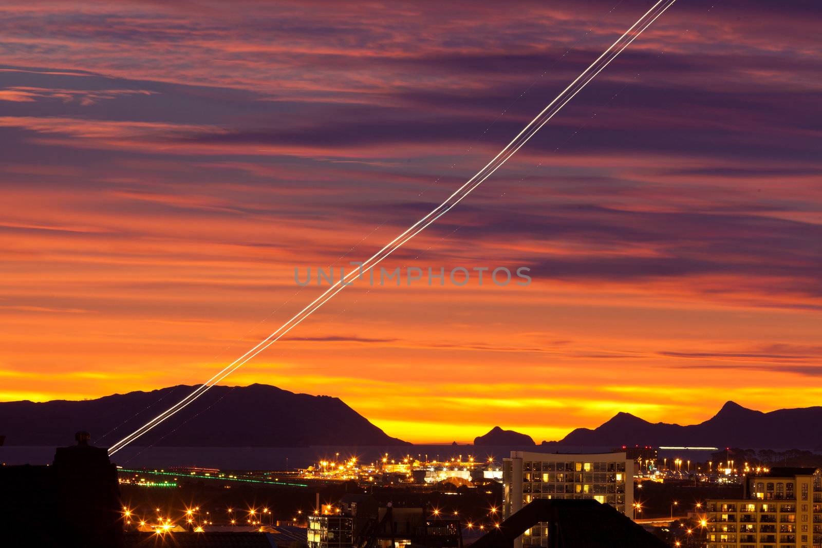 Sunset and light trail of starting airplane over Manukau  southern suburb of Auckland  New Zealand