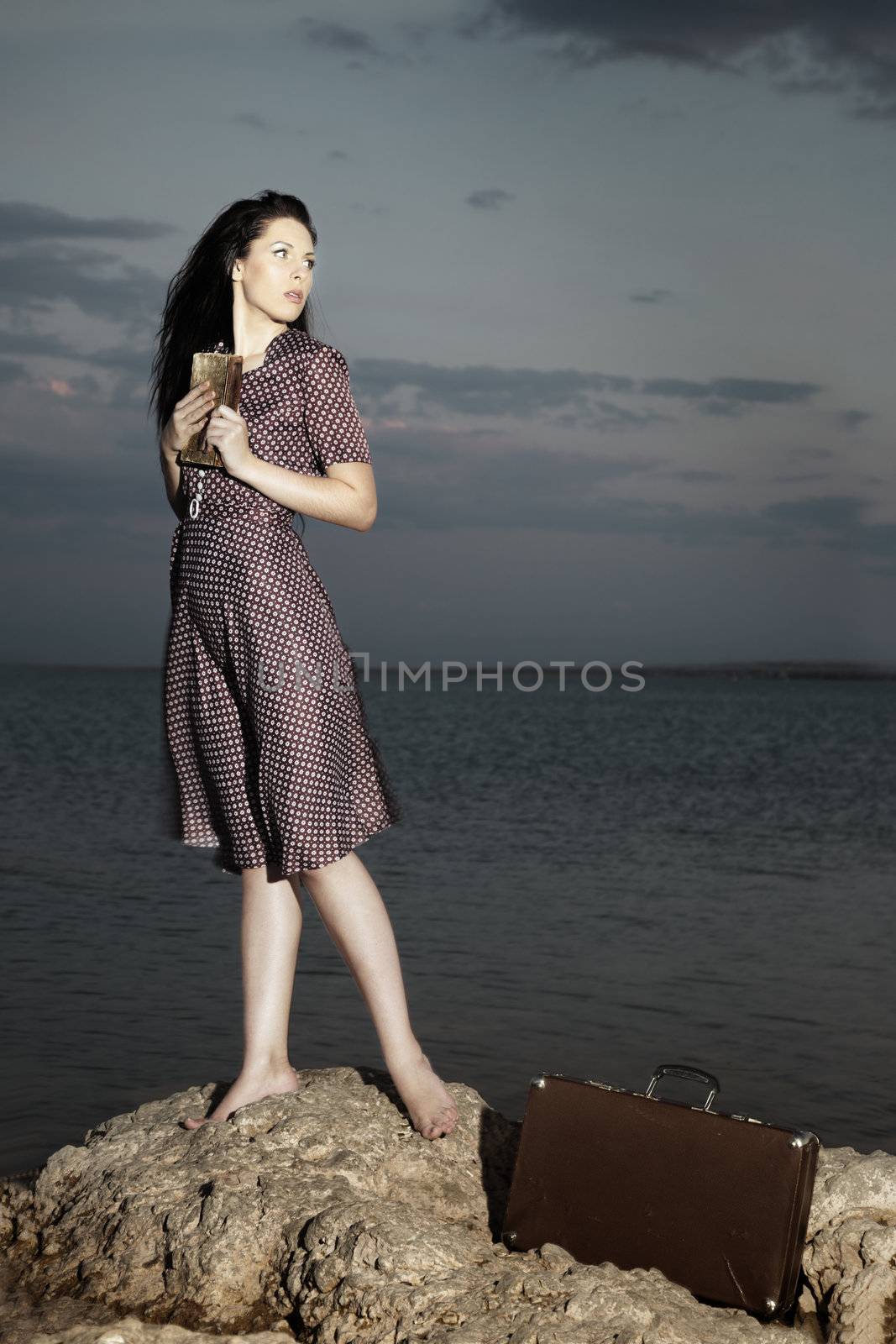 Sensual lady standing at the sea and holding old book