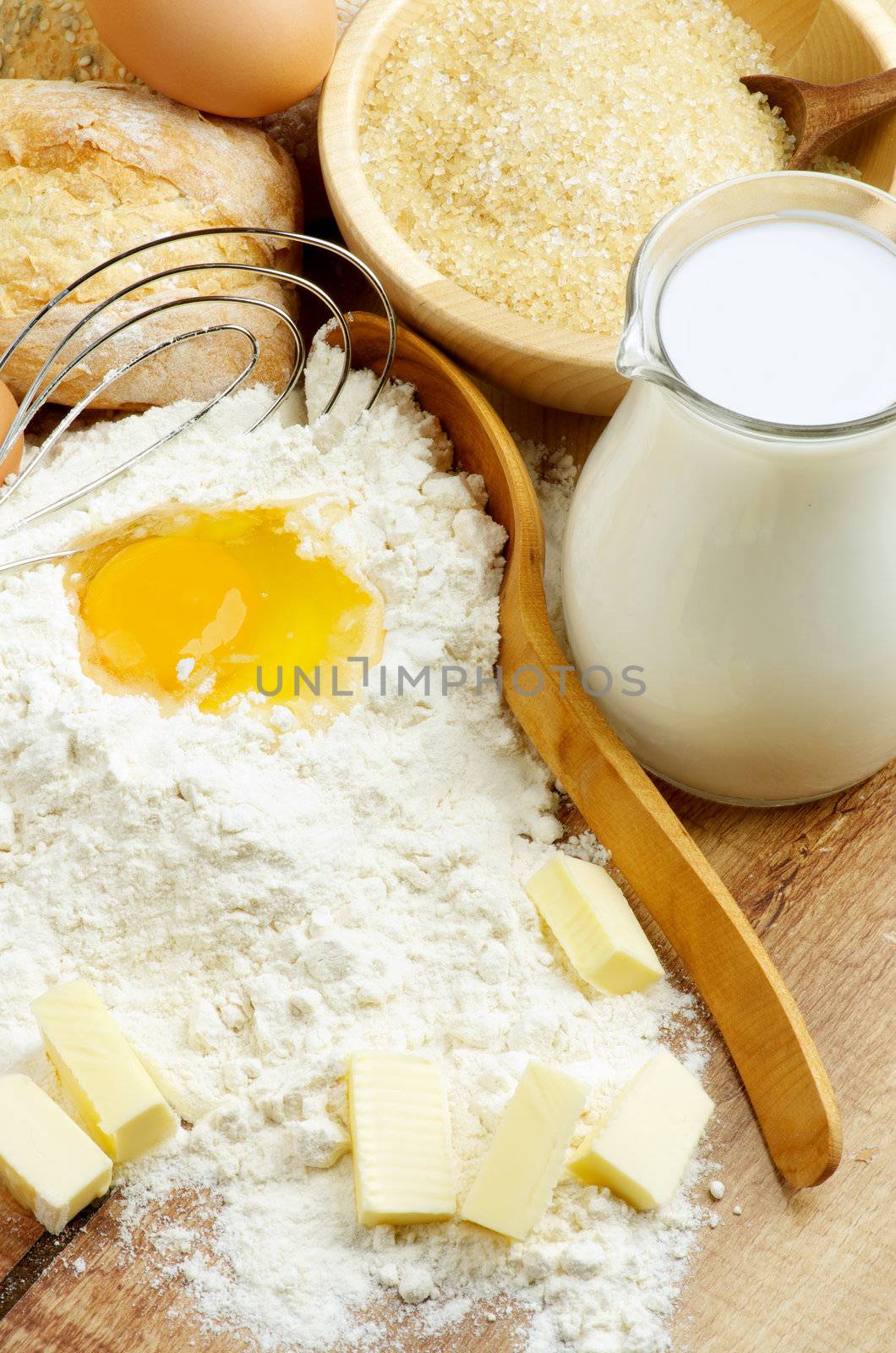 Preparing Dough. Ingredients with Milk, Flour, Butter, Eggs, Sugar and Wooden Spoon with Egg Whisk closeup on Wooden background