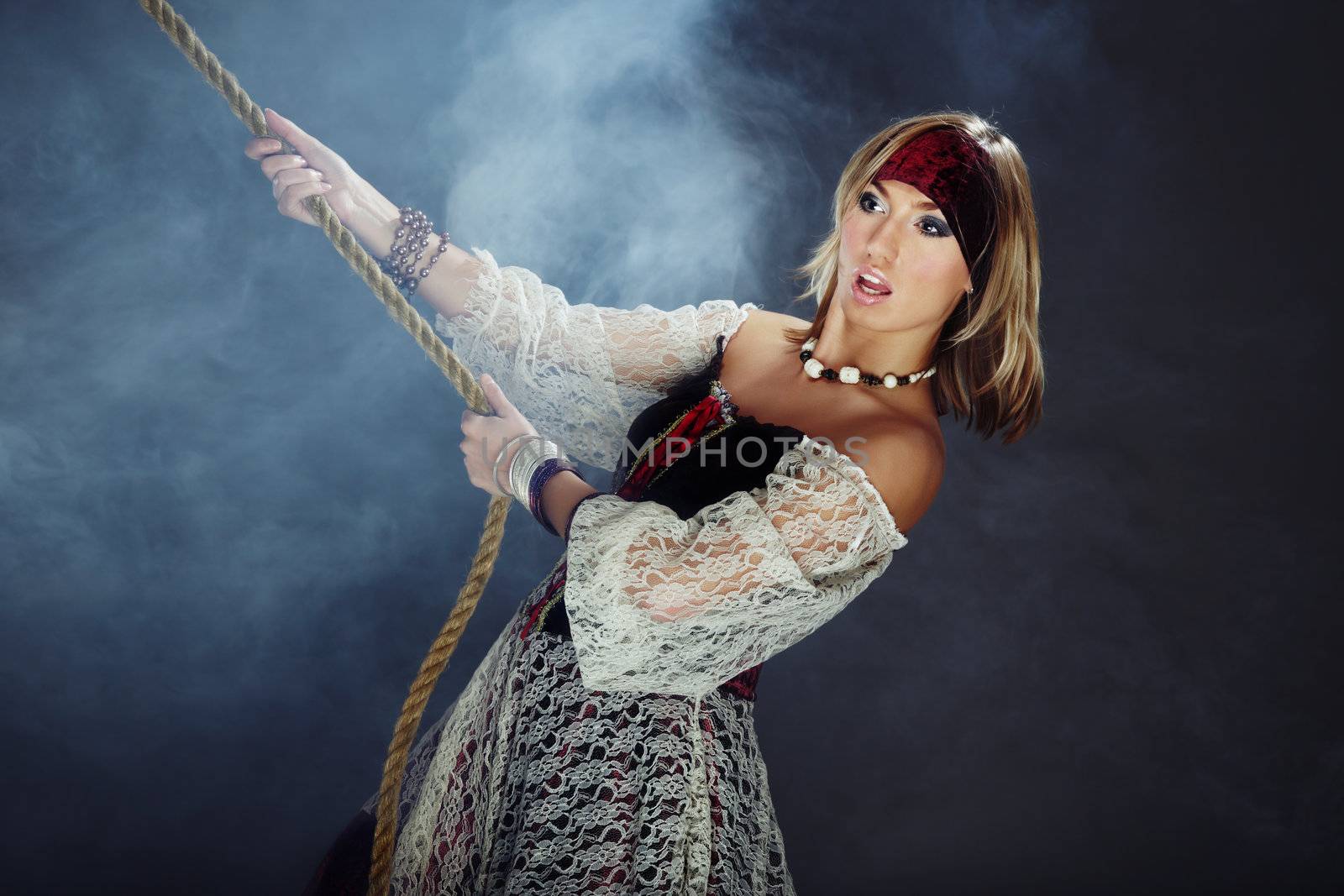 Fashionable lady in the pirate costume holding the rope in the heavy smoke