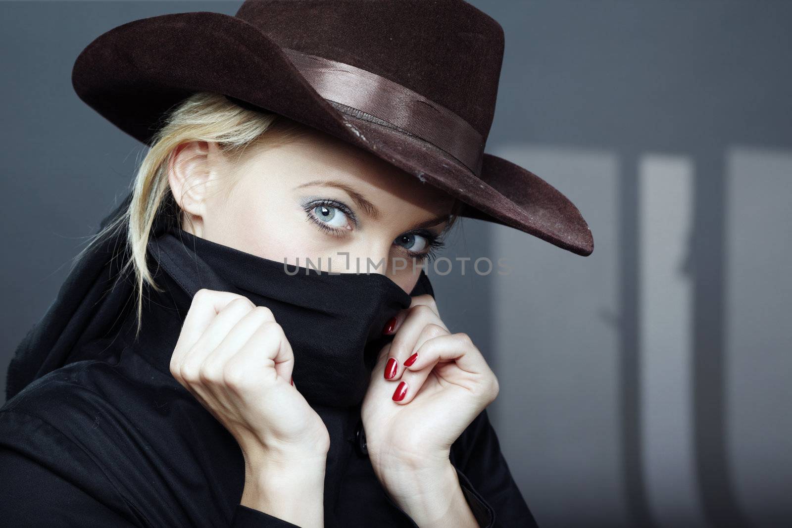 Criminal woman in the black coat and brown hat indoors with dark shadows