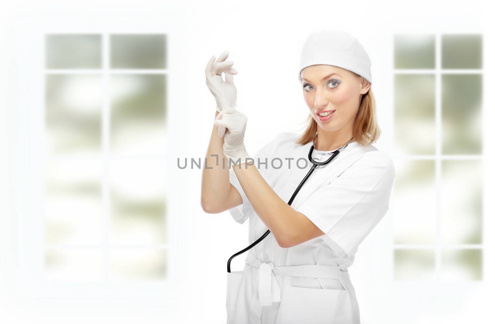 Pretty female doctor putting on the latex gloves in the clinic with big windows