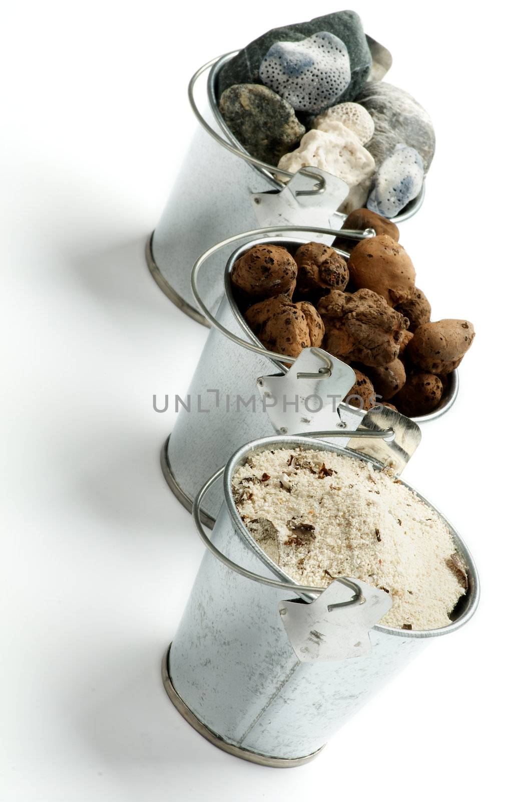 Three Tin Buckets with Gravel, Sand and Stones in a Row isolated on white background