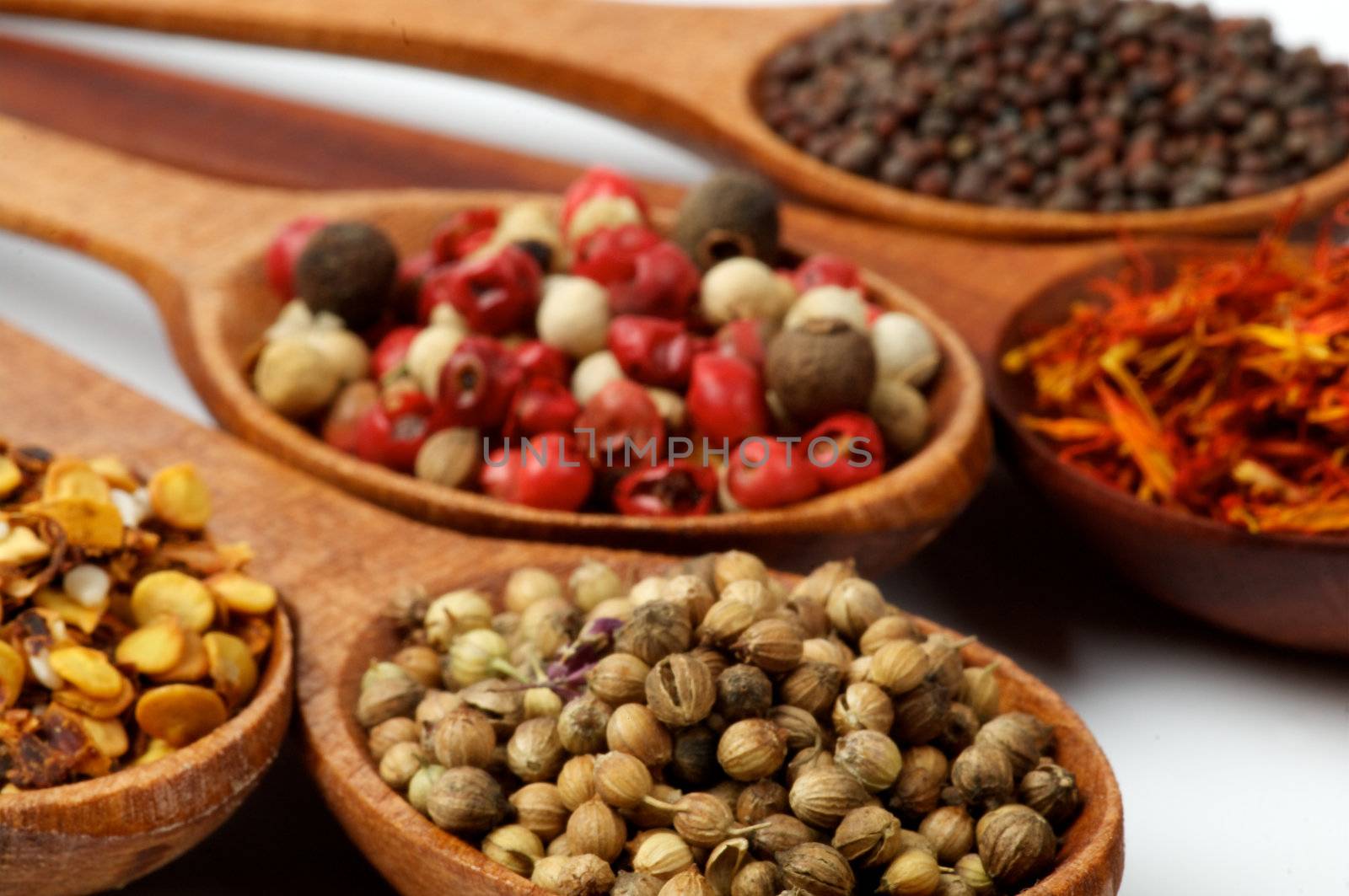 Five Spices in Wooden Spoons close up on white backgroud