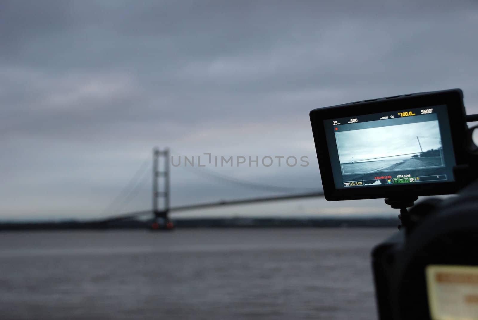 Humber Bridge being filmed from the river bank at dusk on a professional video camera