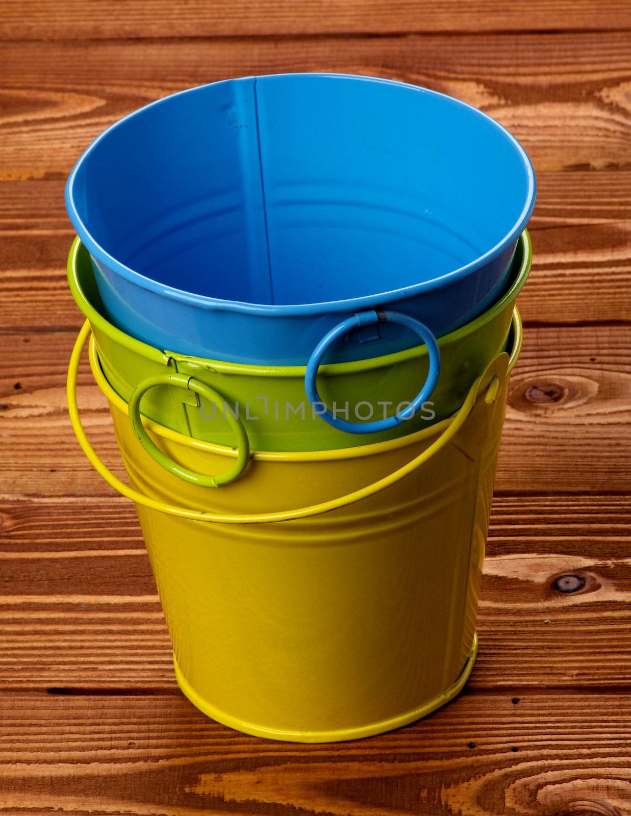 Stack of Three Colour Tin Buckets isolated on wooden background