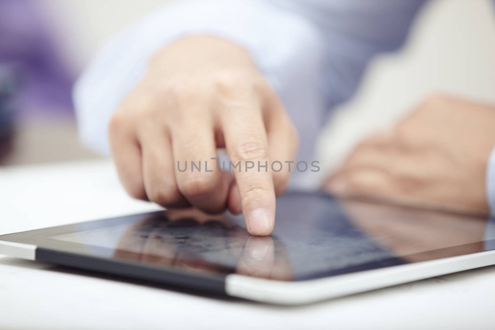 Hands of businessman using tablet PC at office