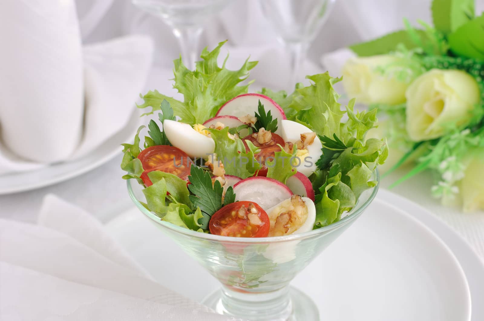 Salad of cherry tomatoes with quail egg and radish in the salad leaves
