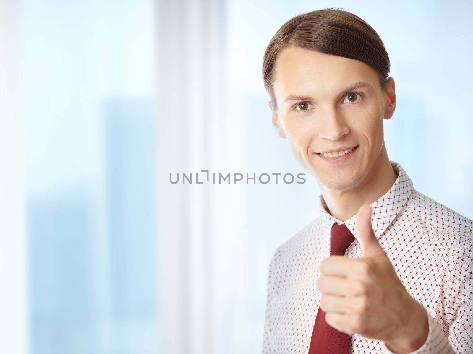 Successful businessman making thumbs up gesture in his office