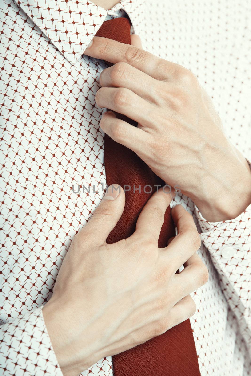 Close-up photo of the businessman knotting his red necktie