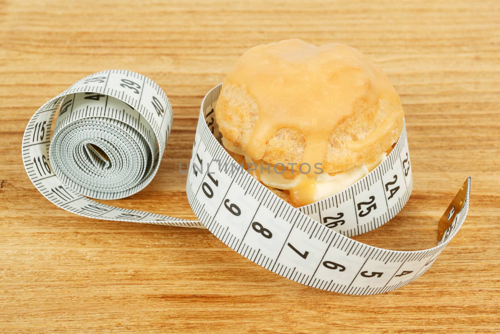 concept of slimming, caramel cake with measuring tape on desk