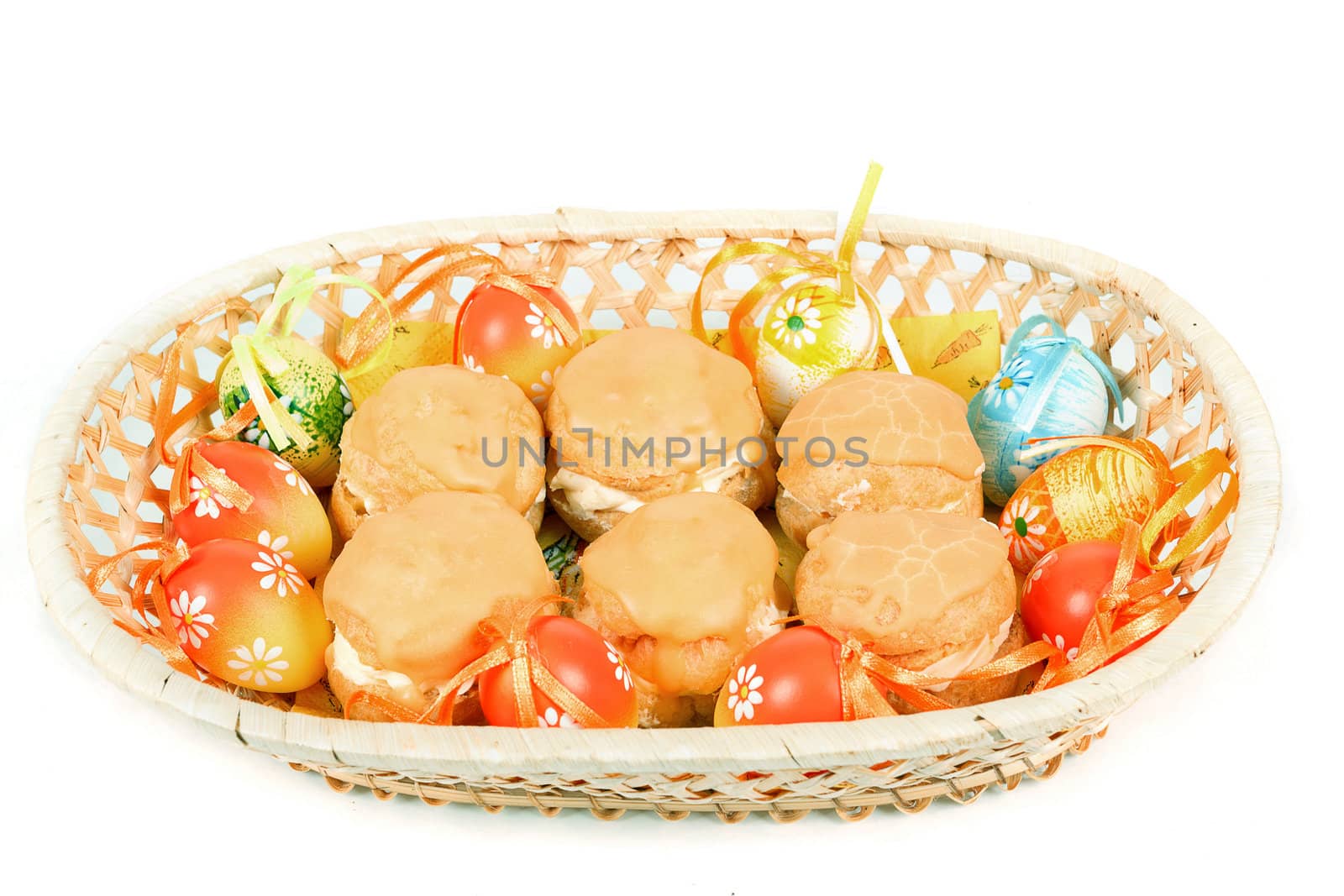 easter eggs and homemade sweet cakes in basket on white