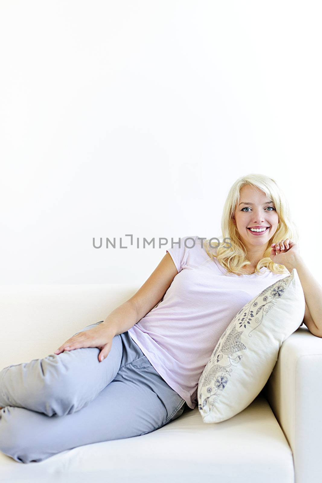 Beautiful blonde woman reclining on couch and relaxing at home