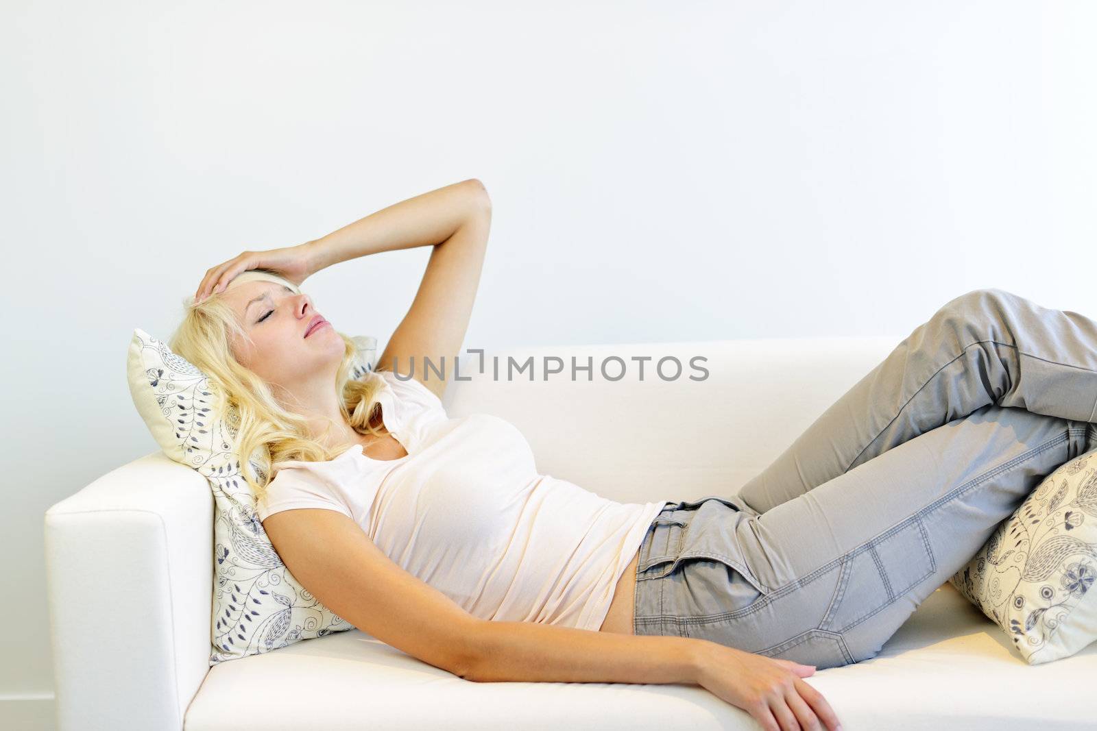 Stressed tired woman lying on couch with eyes closed at home