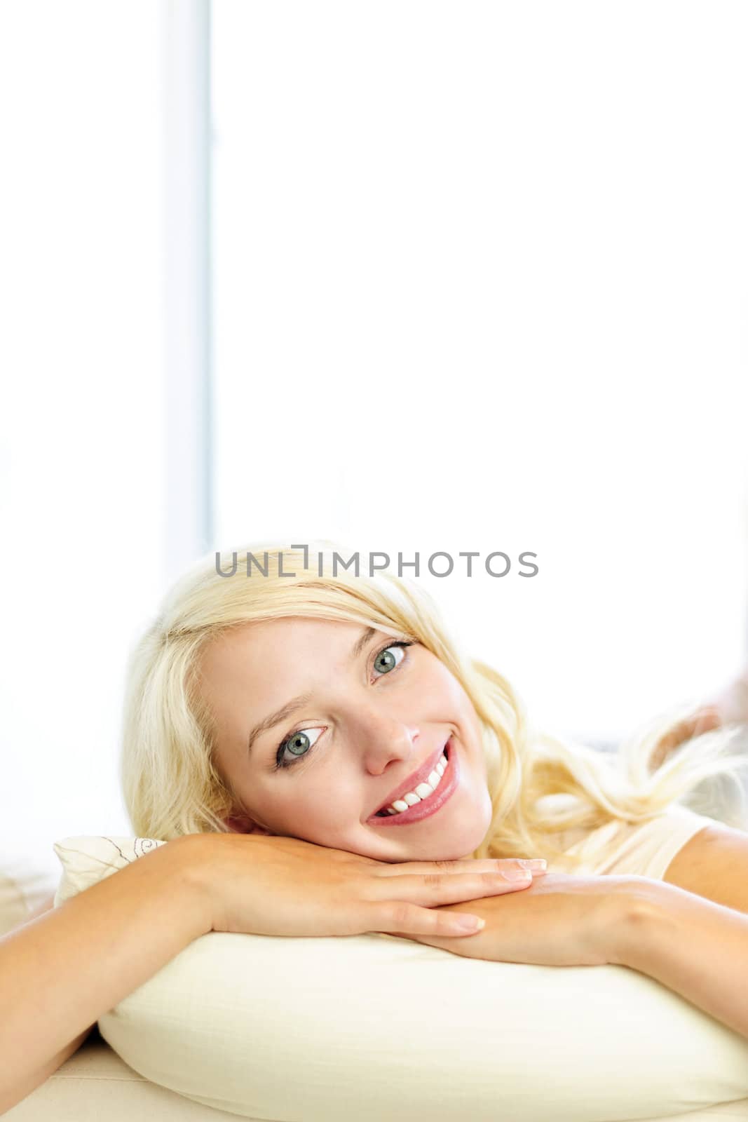 Portrait of happy blonde woman relaxing and smiling on couch