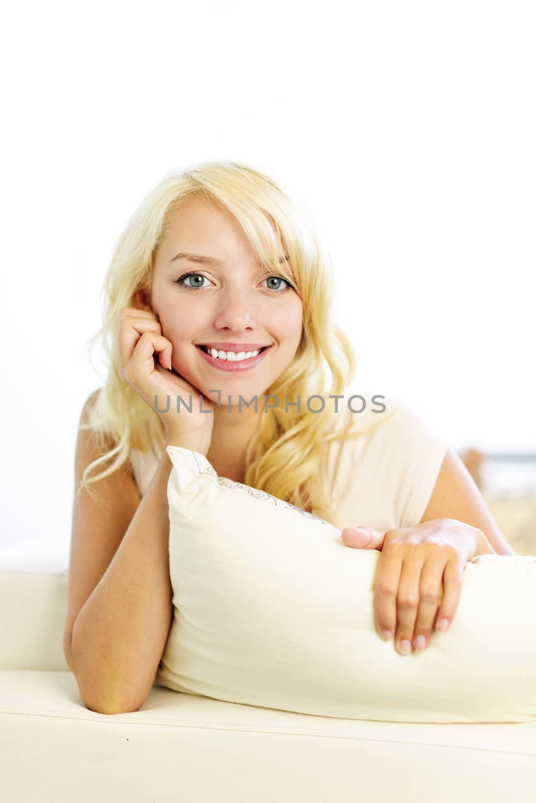 Portrait of smiling blonde woman relaxing on couch in living room at home