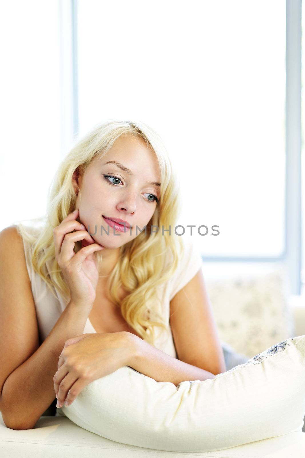 Portrait of thoughtful blonde woman relaxing on couch at home