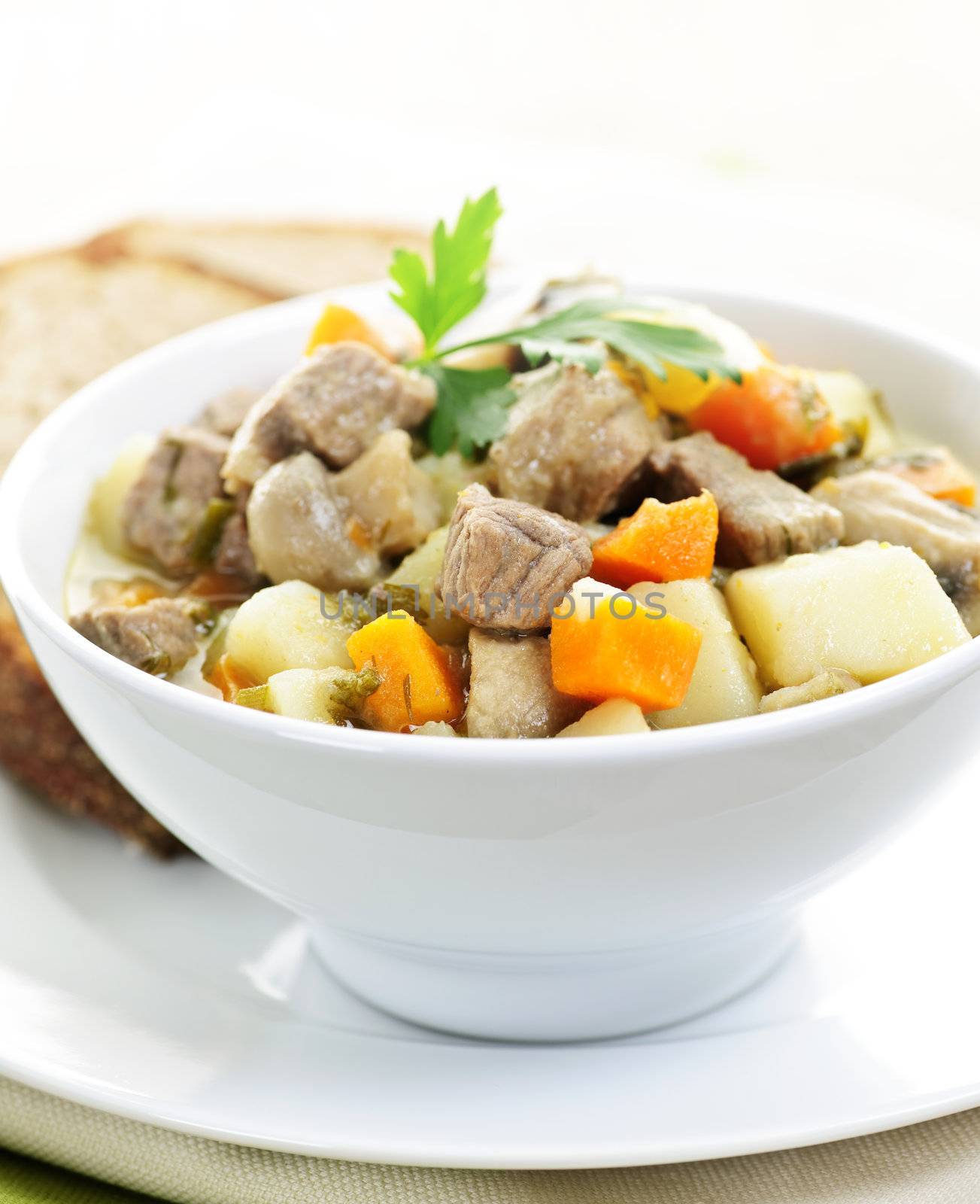 Bowl of hearty beef stew with vegetables served with rye bread