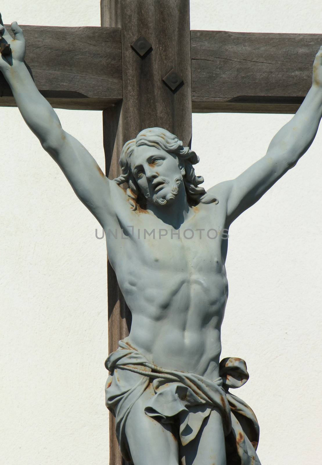 Close up of green statue of Jesus-Christ on a wood cross