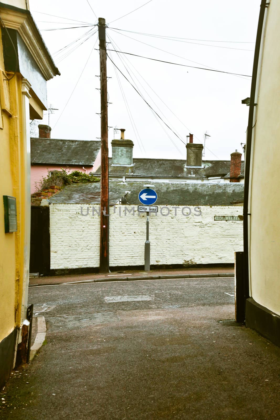 One way sign on a street seen through an alley way