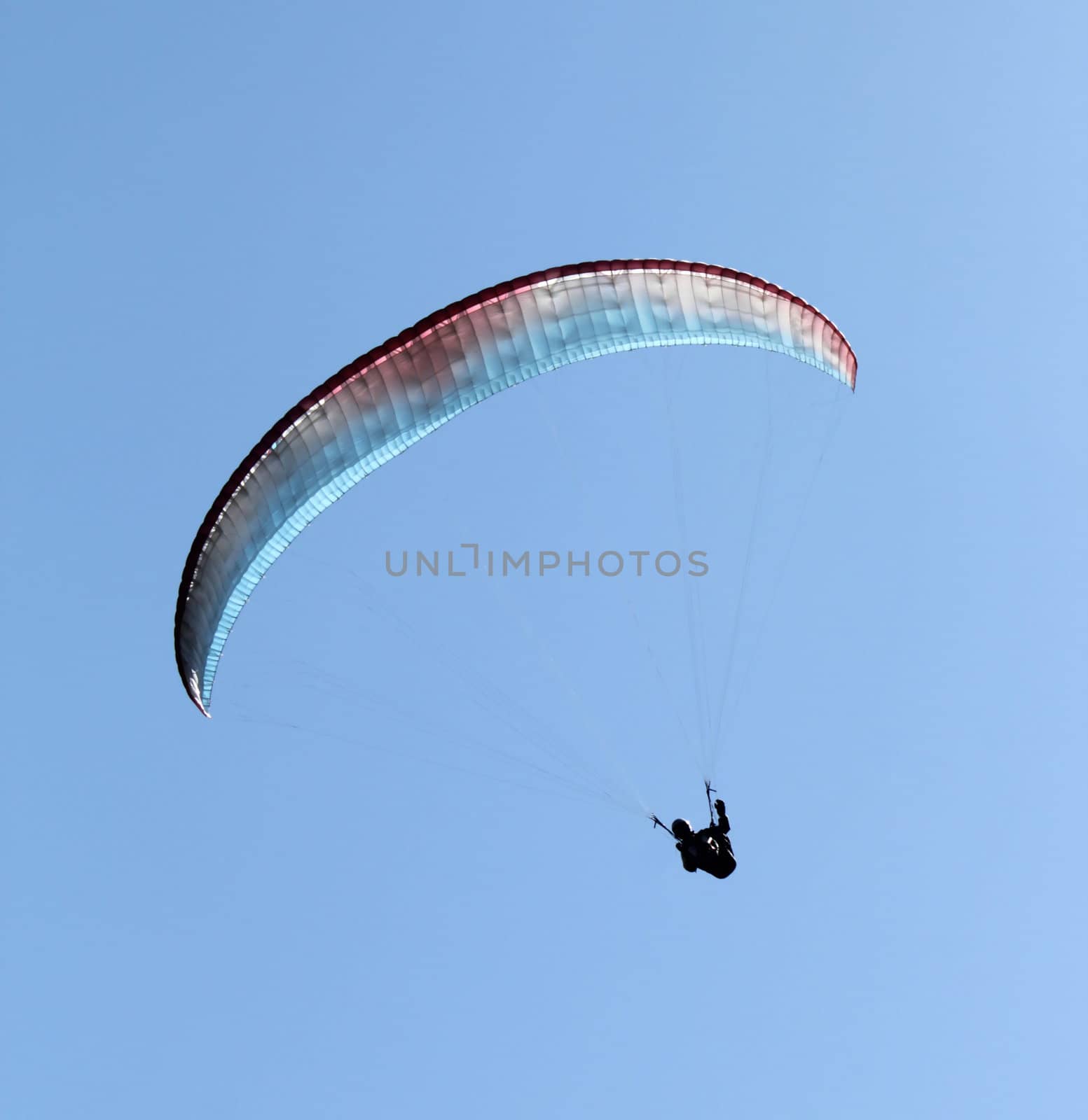 Paraglider flying with colordul paraglide in the blue sky