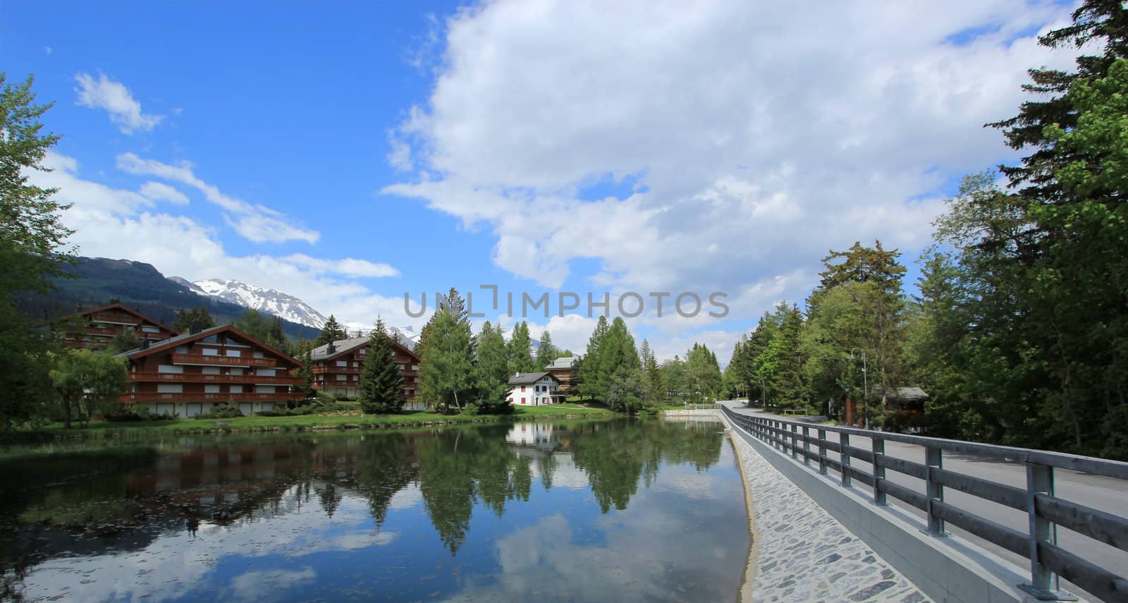 Small houses reflecting in the white lake by summer, Crans Montana, Switzerland