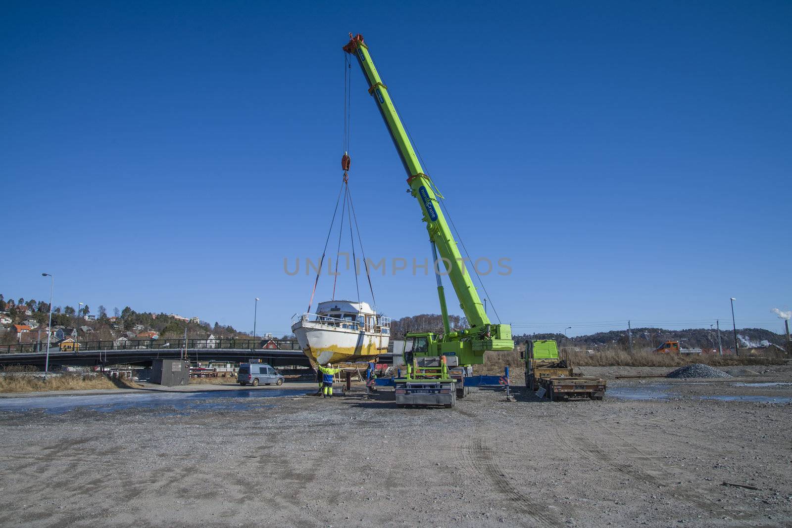 The boat was transported by trailer and was unloaded with a huge mobile crane on the quay at the port of Halden, Norway. The picture is shot one day in March.