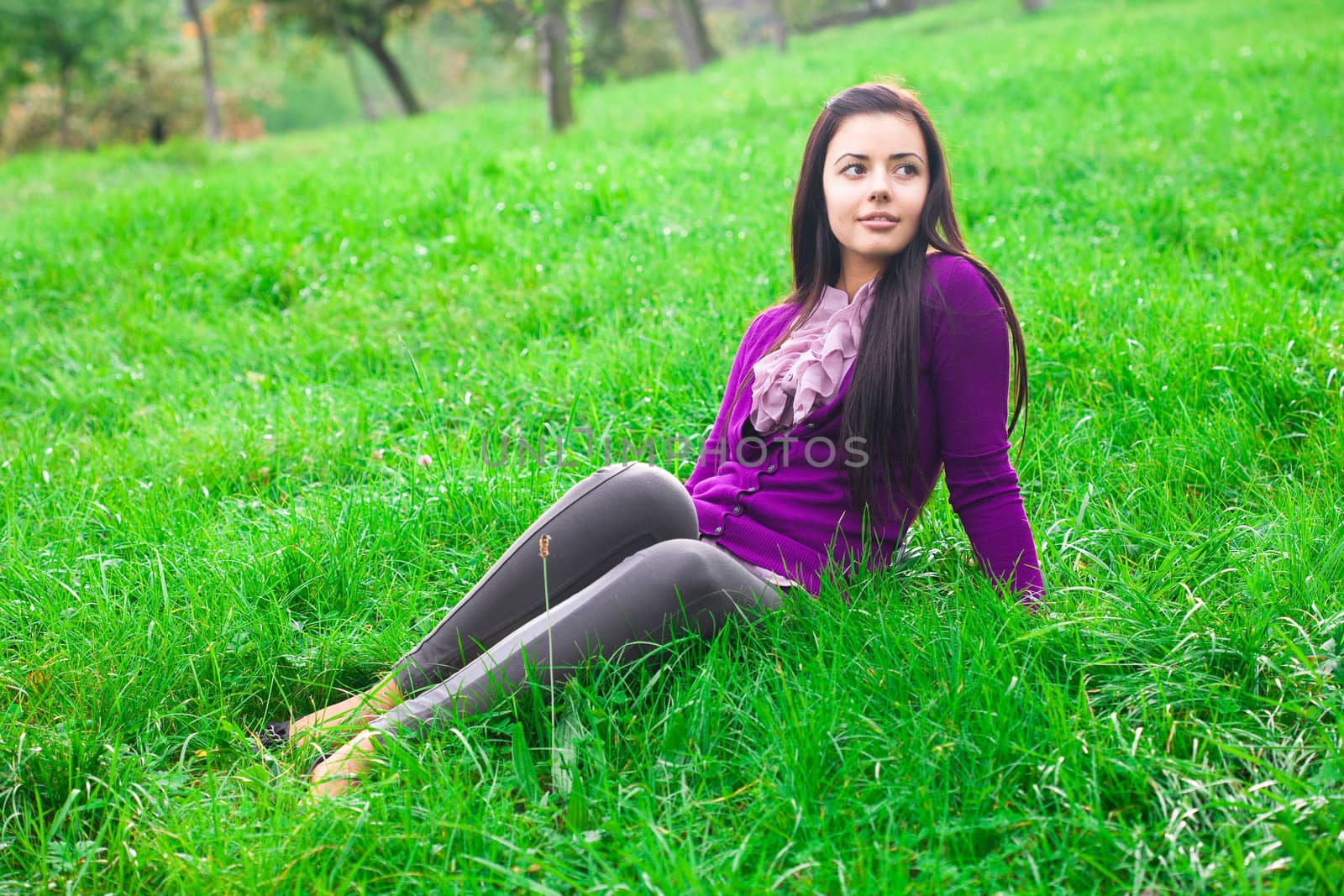 beautiful young woman sitting on green grass