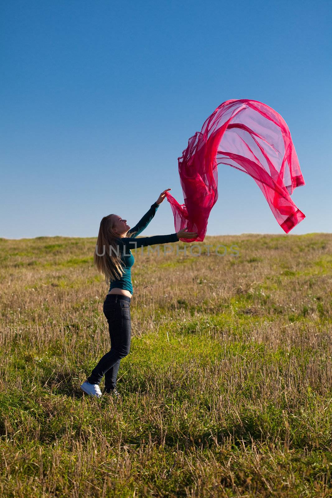 young beautiful woman jumping with tissue into the field against the sky