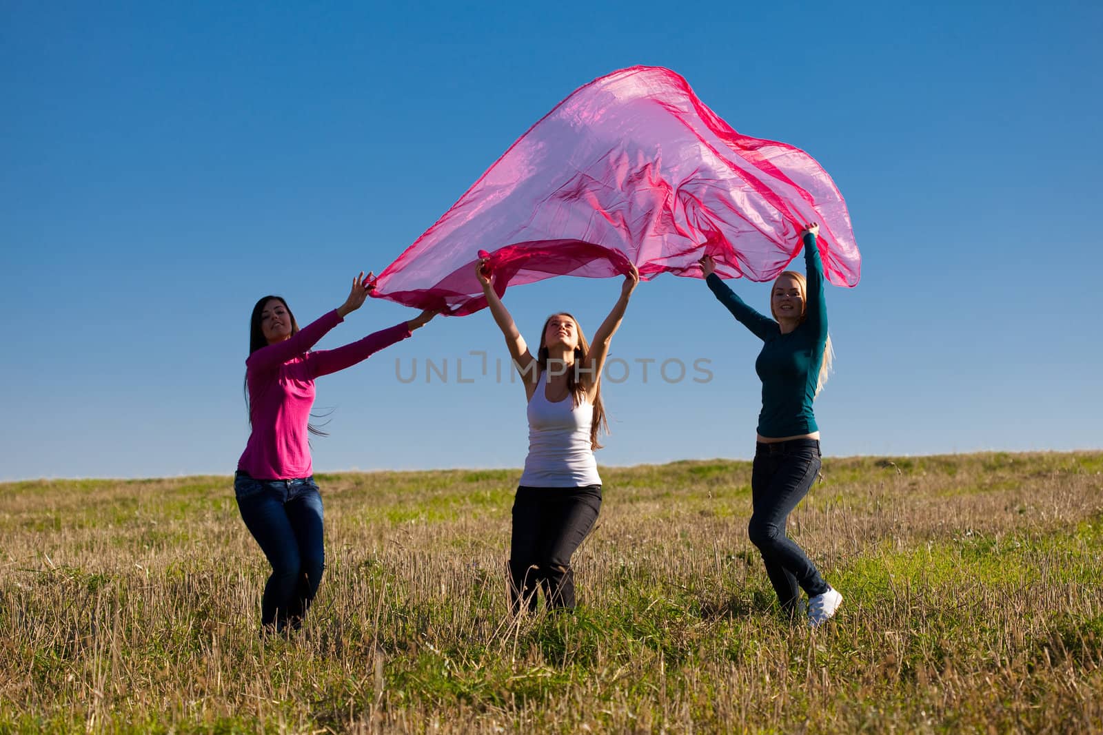 three young beautiful woman jumping with tissue into the field a by jannyjus