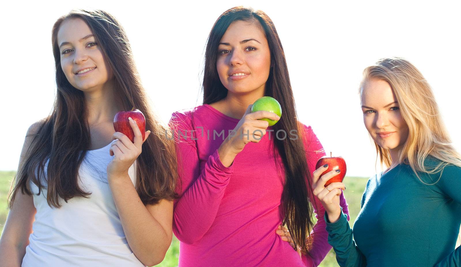 portret of three young beautiful woman with apple on the  sky ba by jannyjus