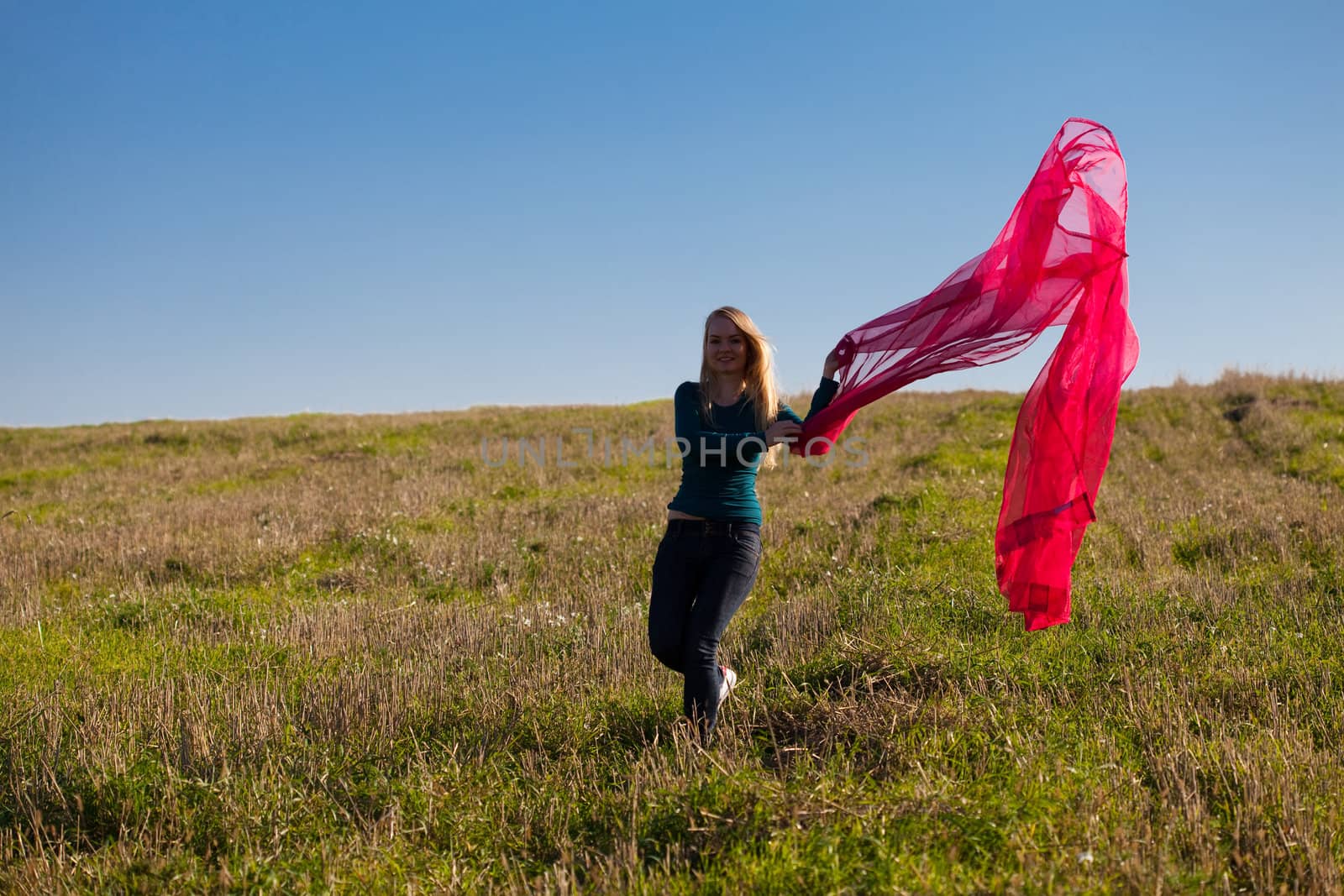 young beautiful woman jumping with tissue into the field against the sky