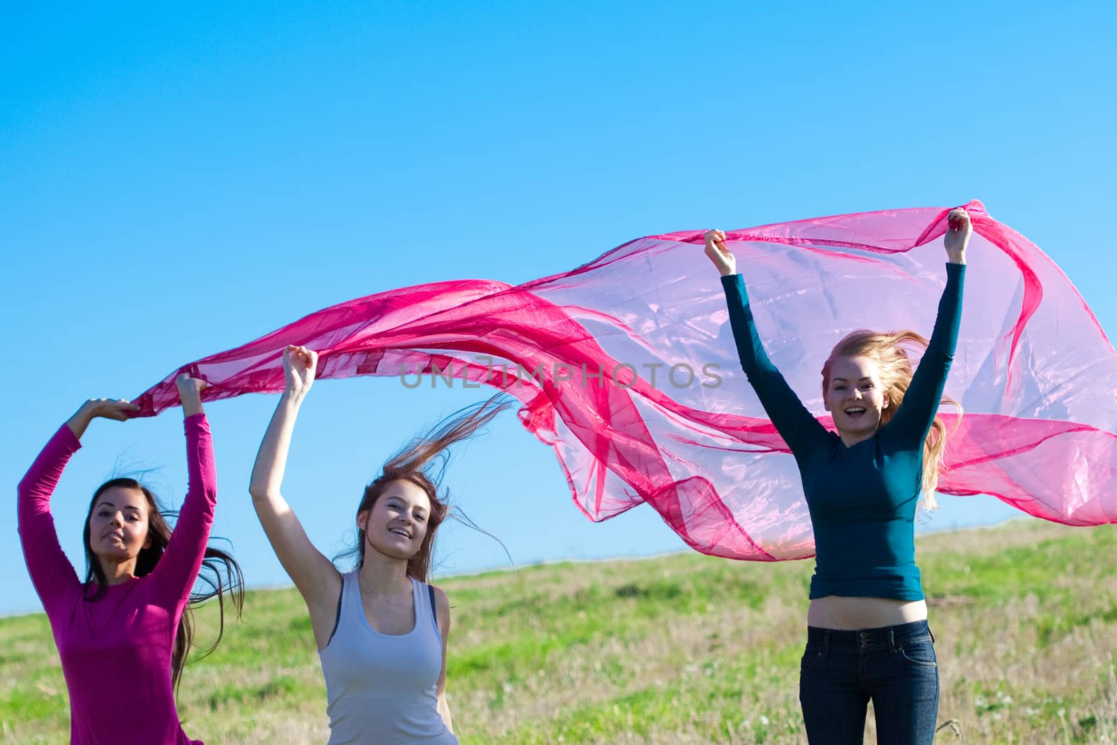 three young beautiful woman jumping with tissue into the field a by jannyjus