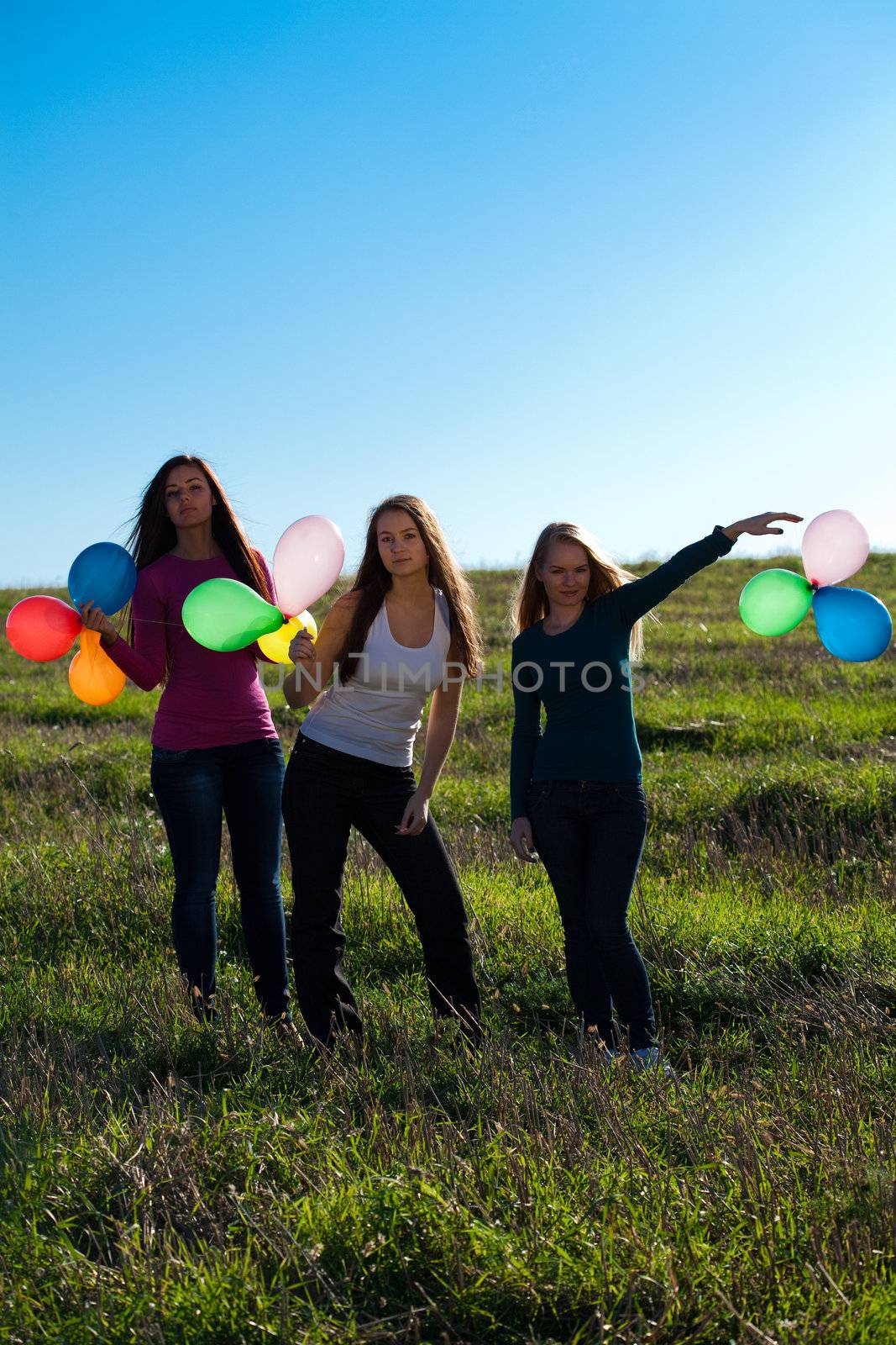 three young beautiful woman with balloons into the field against by jannyjus