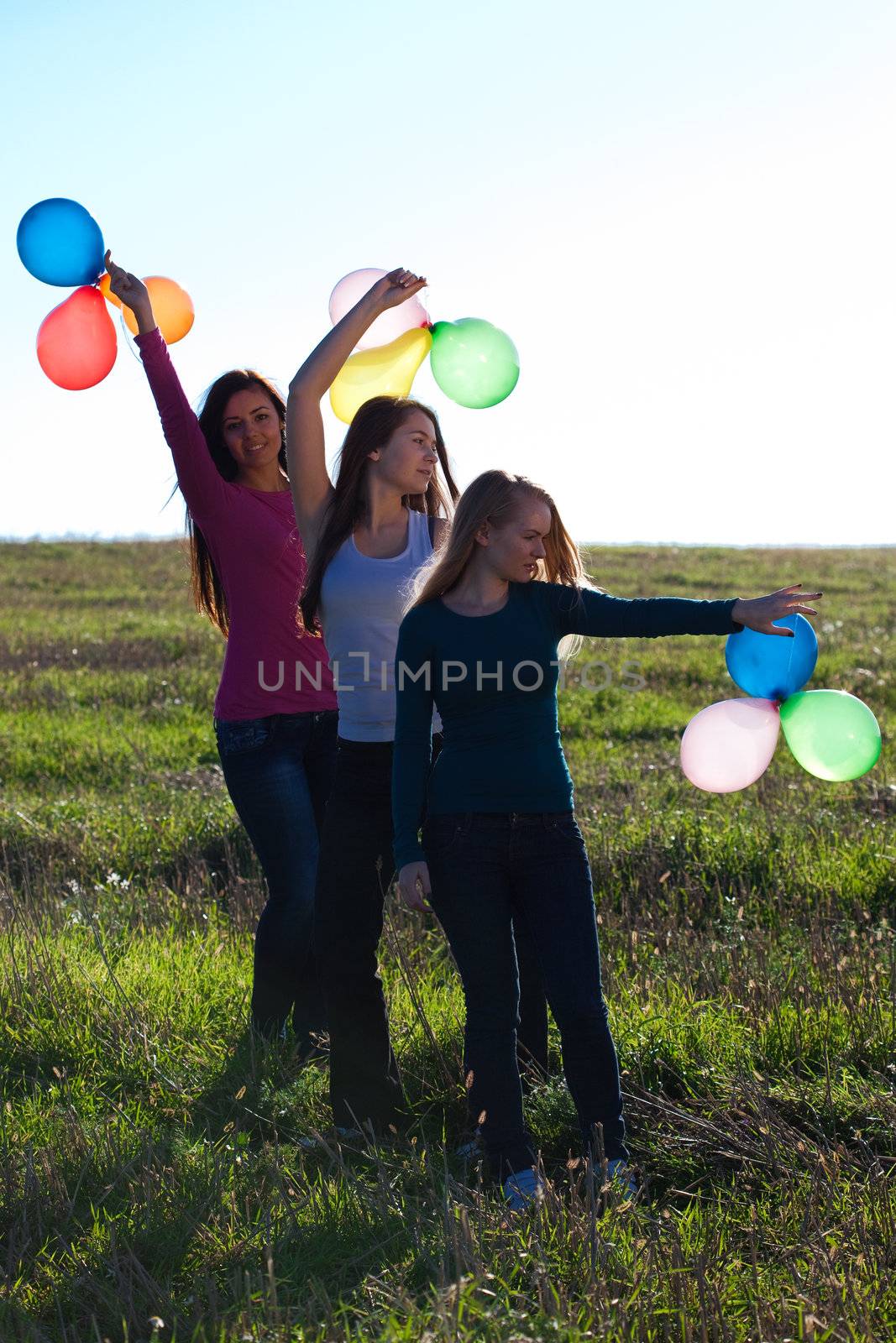 three young beautiful woman with balloons into the field against by jannyjus