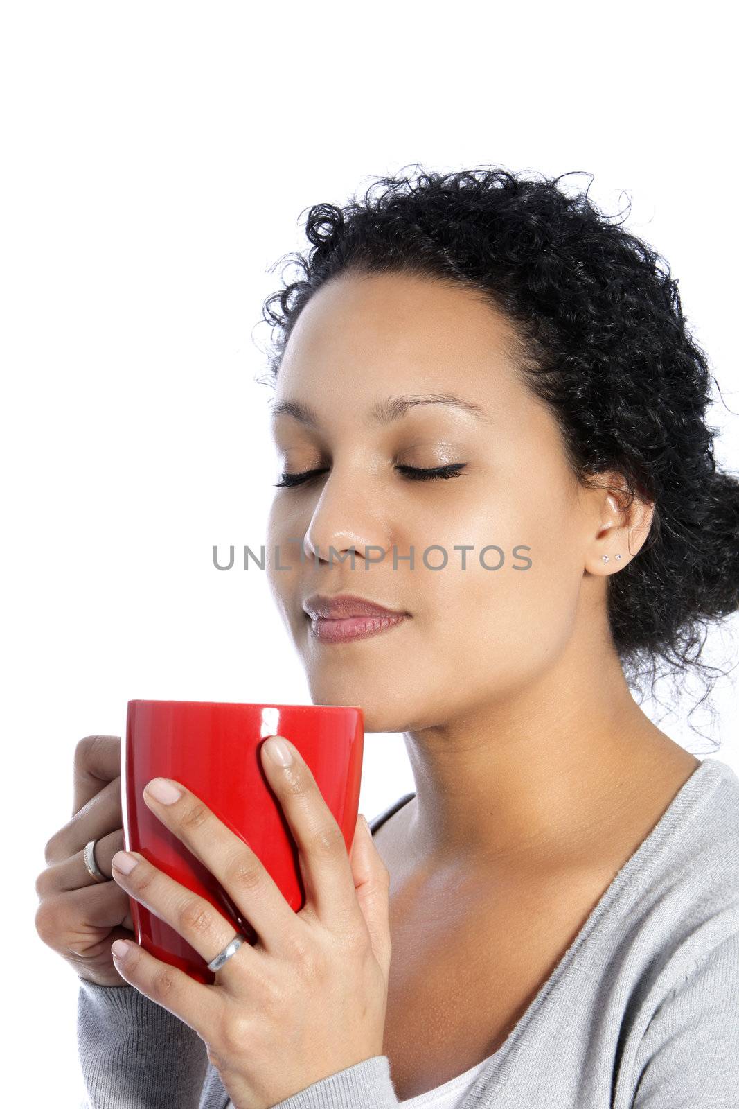 Beautiful African American woman standing with her eyes closed enjoying the aroma of a mug of coffee isolated on white
