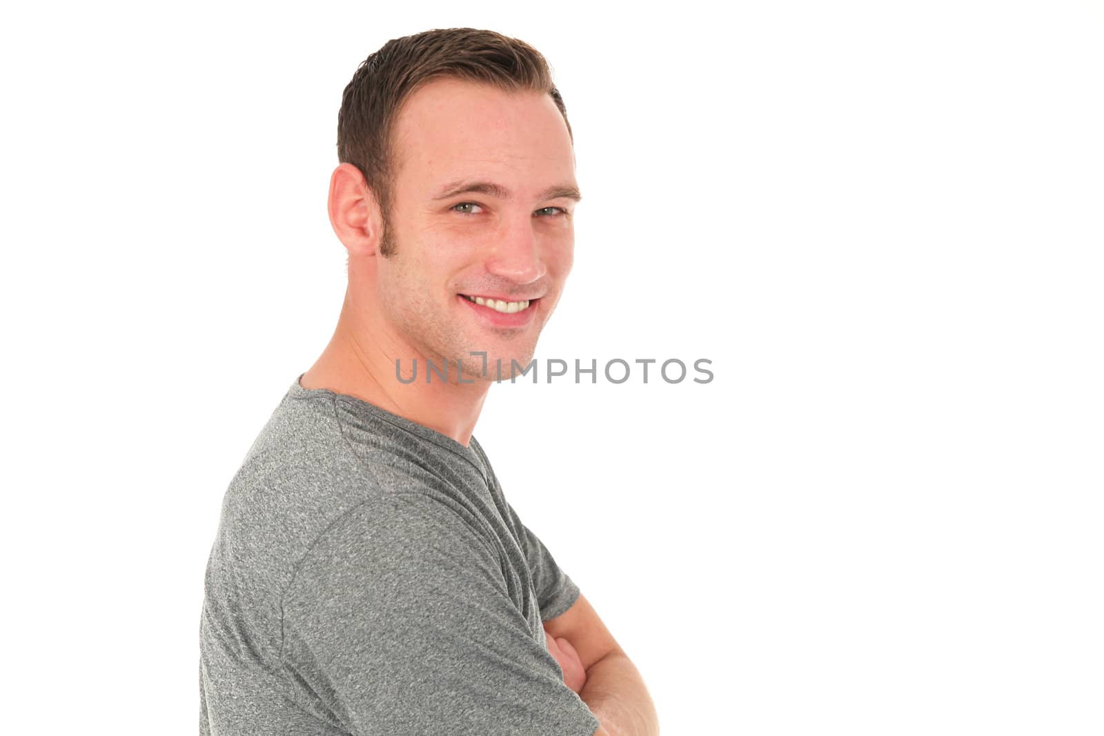 Handsome casual young man standing sideways and smiling as he looks at the camera isolated on white