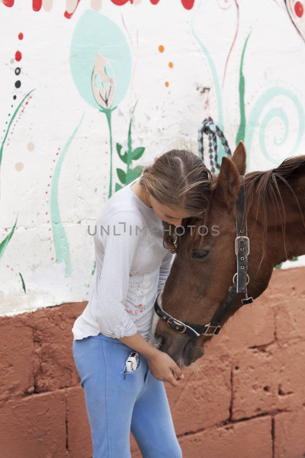 A teenage girl embracing her horse. Real people.