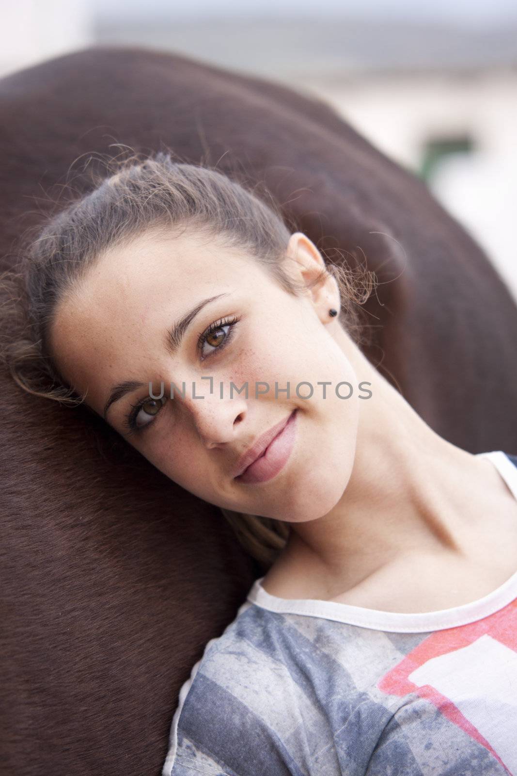 Pretty girl, dressed in an american flag tshirt, resting on her horse, looking at camera