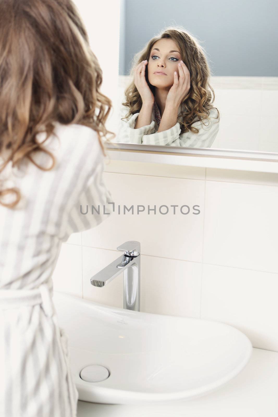 Young beautiful girl looks in the mirror