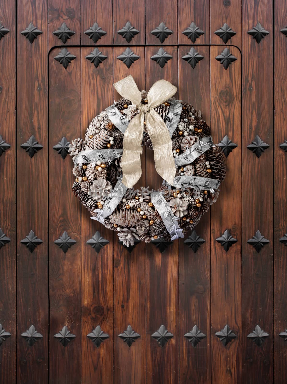 Traditional Christmas wreath in silver and gold on wooden door