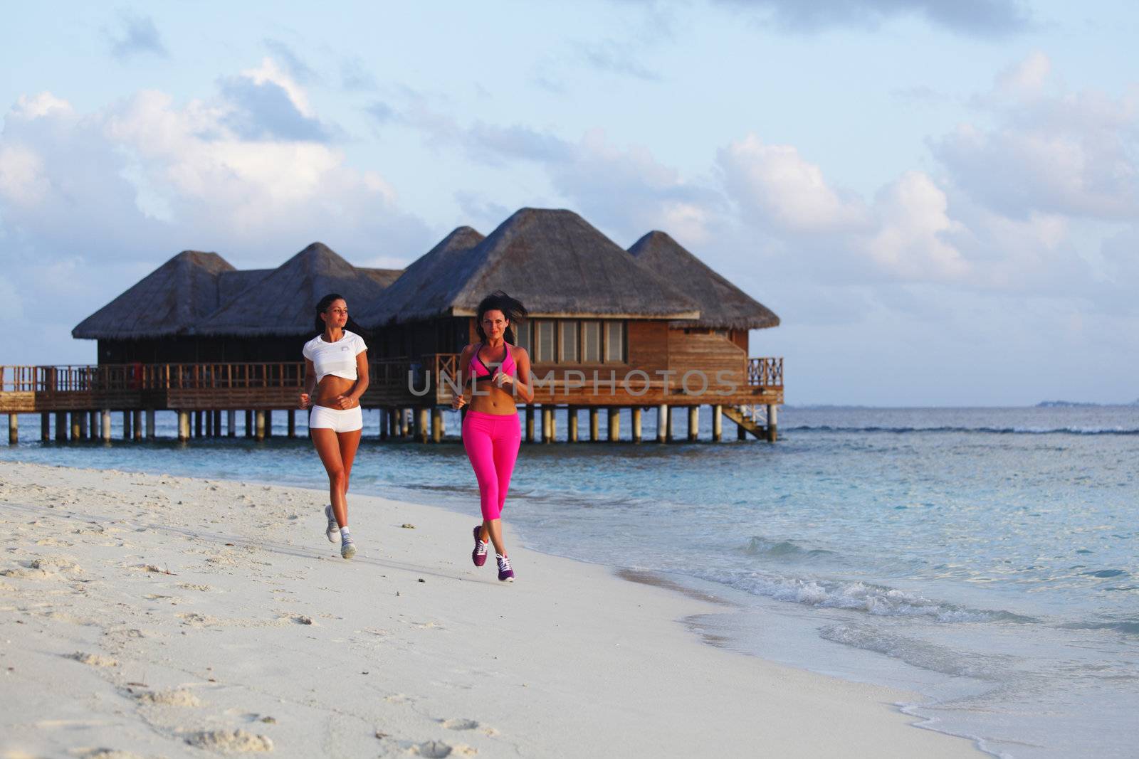 Two women running on beach by Yellowj