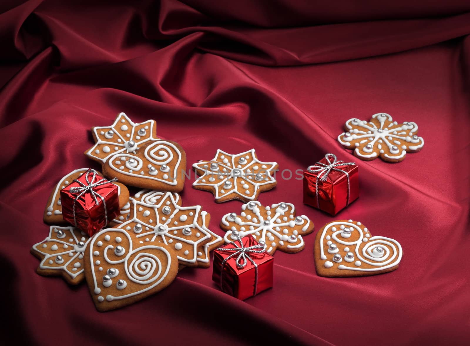 Decorated Christmas gingerbread cookies on red silky textile background