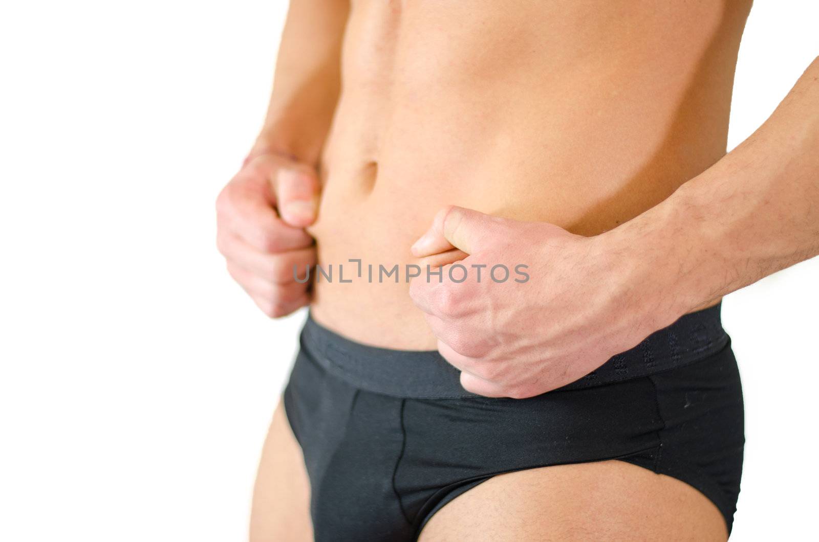 Fit, athletic young man pinching his stomach skin and showing abs