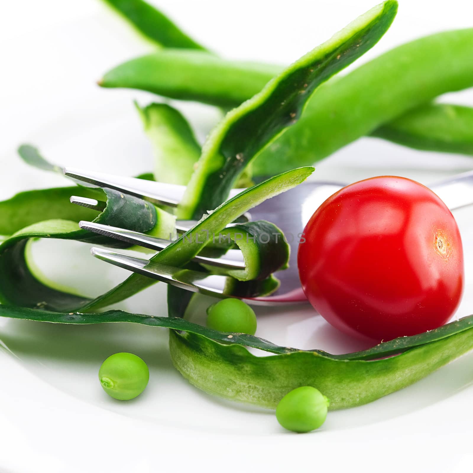tomato,fork ,cucumber skin,peas and measure tape on a plate isolated on white