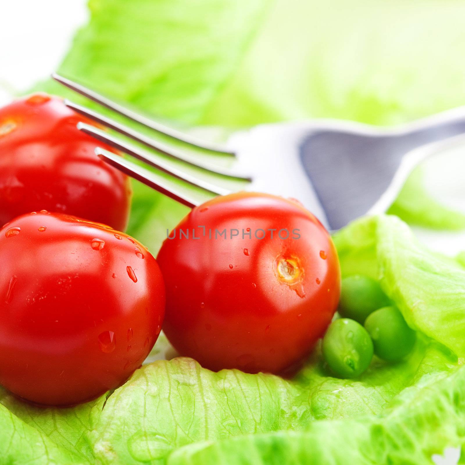 tomato,peas and lettuce with a fork on a plate isolated on white by jannyjus
