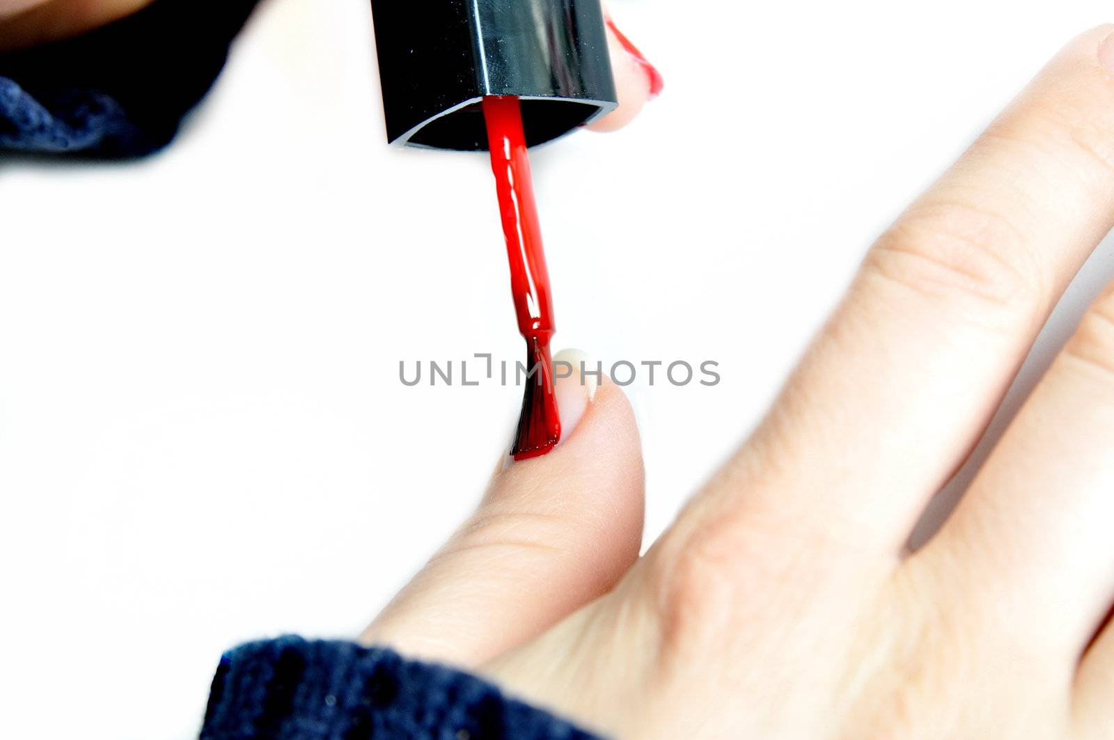 Young girl painting her nails red by anderm